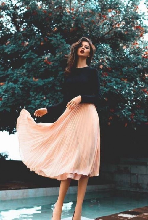 a black long sleeve top and a peachy pink pleated midi skirt for a simple and casual look