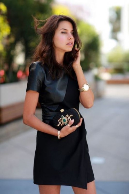 a black mini dress of leather and suede, with an asymmetrical skirt, an embellished snake clutch