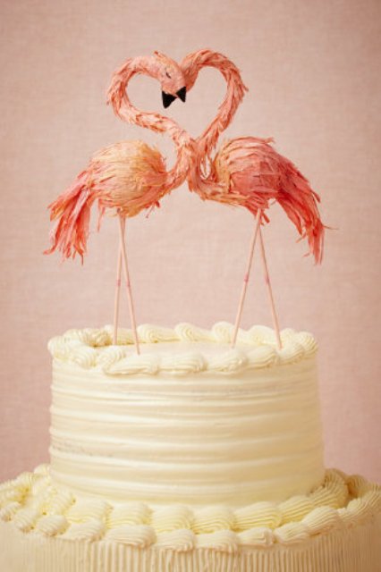 a white wedding cake topped with pink sugar flamingos is a fun and cool idea for a tropical wedding