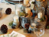 a rustic winter tablescape with stumps, pinecones, candles, gold chargers and moss
