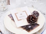 a frozen winter tablescape with bark, pinecones, a snowflake placemat, marshmallows in jars