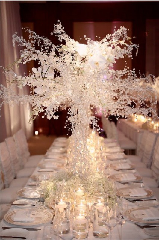 a frozen winter wedding table with frozen branches and crystals, baby's breath and floating candles