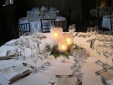 a winter wedding tablescape with candles with evergreens, neutral menus and white napkins is timelessly elegant