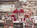 a taupe and red winter wedding tablescape with red blooms, pink lamps, red glasses and vases and silver cutlery