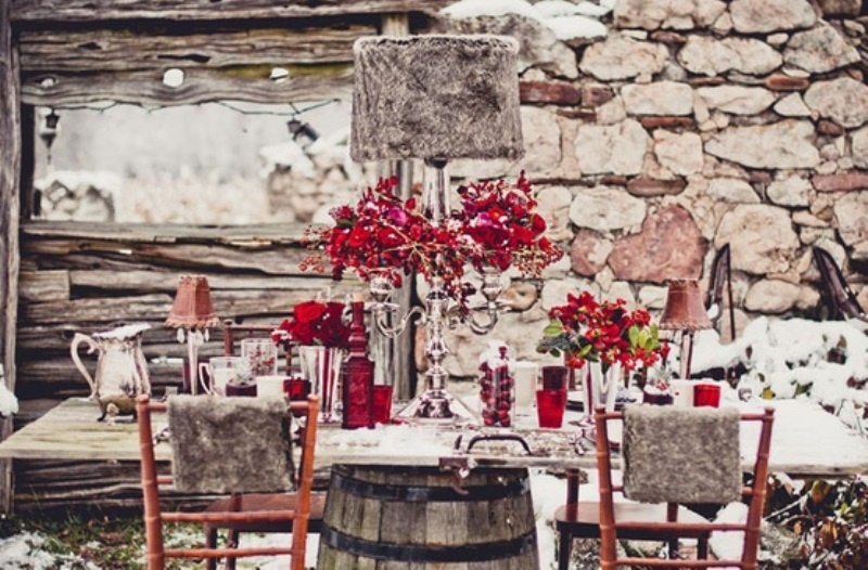 a taupe and red winter wedding tablescape with red blooms, pink lamps, red glasses and vases and silver cutlery