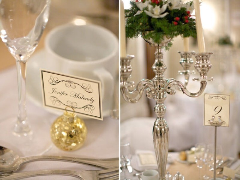 an elegant winter wedding tablescape with shiny ornaments, a silver candelabra with evergreens, berries and white blooms
