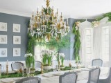 a winter wedding tablescape done with lots of evergreens, candles, blooms in pots, a large crystal chandelier with candles