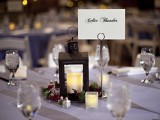 a neutral winter wedding table with glasses, candles, a candle lantern centerpiece in a wreath