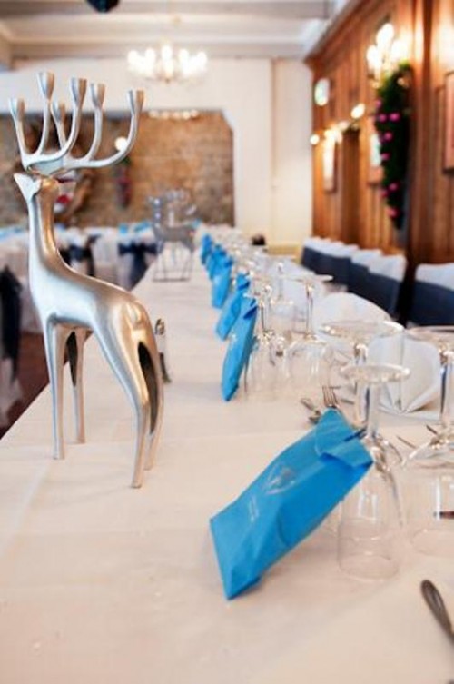 a neutral winter wedding tablescape with bright blue accents and silver deer figurines for a lodge wedding