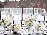 an all-neutral winter wedding table setting with lush white floral centerpieces, white porcelain and neutral napkins plus silver cutlery