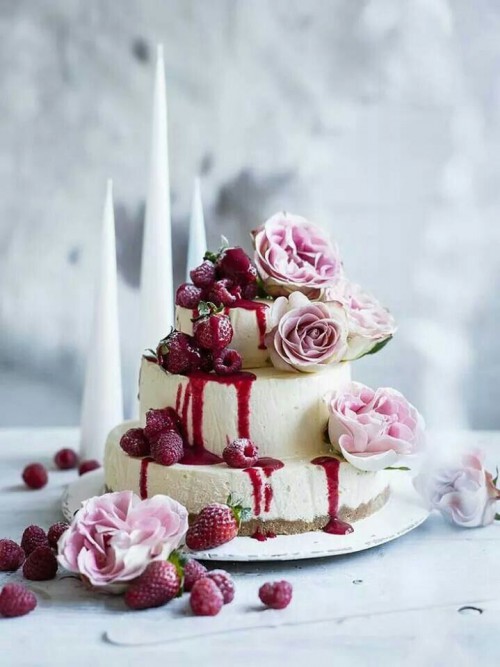 a three-tiered white chocolate cheesecake with fresh raspberries and strawberries, pink roses is a refined idea