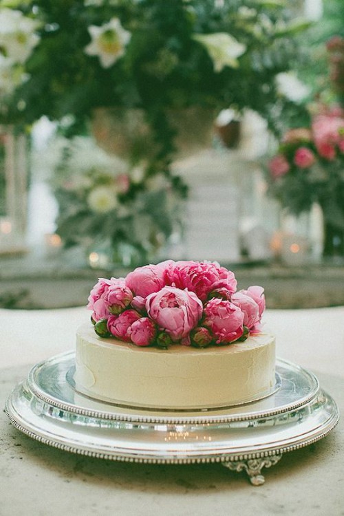 a white chocolate covered wedding cheesecake topped with fresh pink peonies