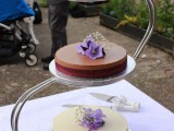 a classic, chocolate and berry wedding cheesecake on stands topped with fresh blooms