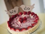 a strawberry wedding cheesecake with fresh berries and swirl decor plus funny bird toppers