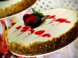 a strawberry wedding cheesecake with swirls and a red rose looks romantic and dramatic