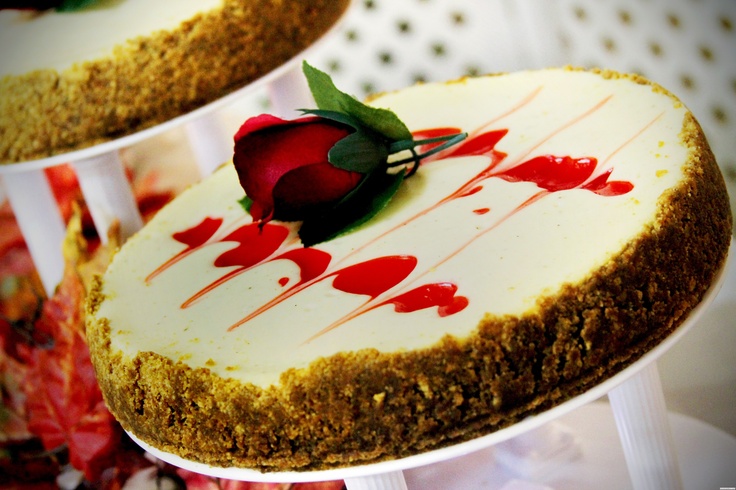 A strawberry wedding cheesecake with swirls and a red rose looks romantic and dramatic