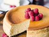a large wedding cheesecake with chocolate base topped with fresh raspberries