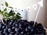 a classic cheesecake decorated with white chocolate petals and lots of blueberries on top plus a banner